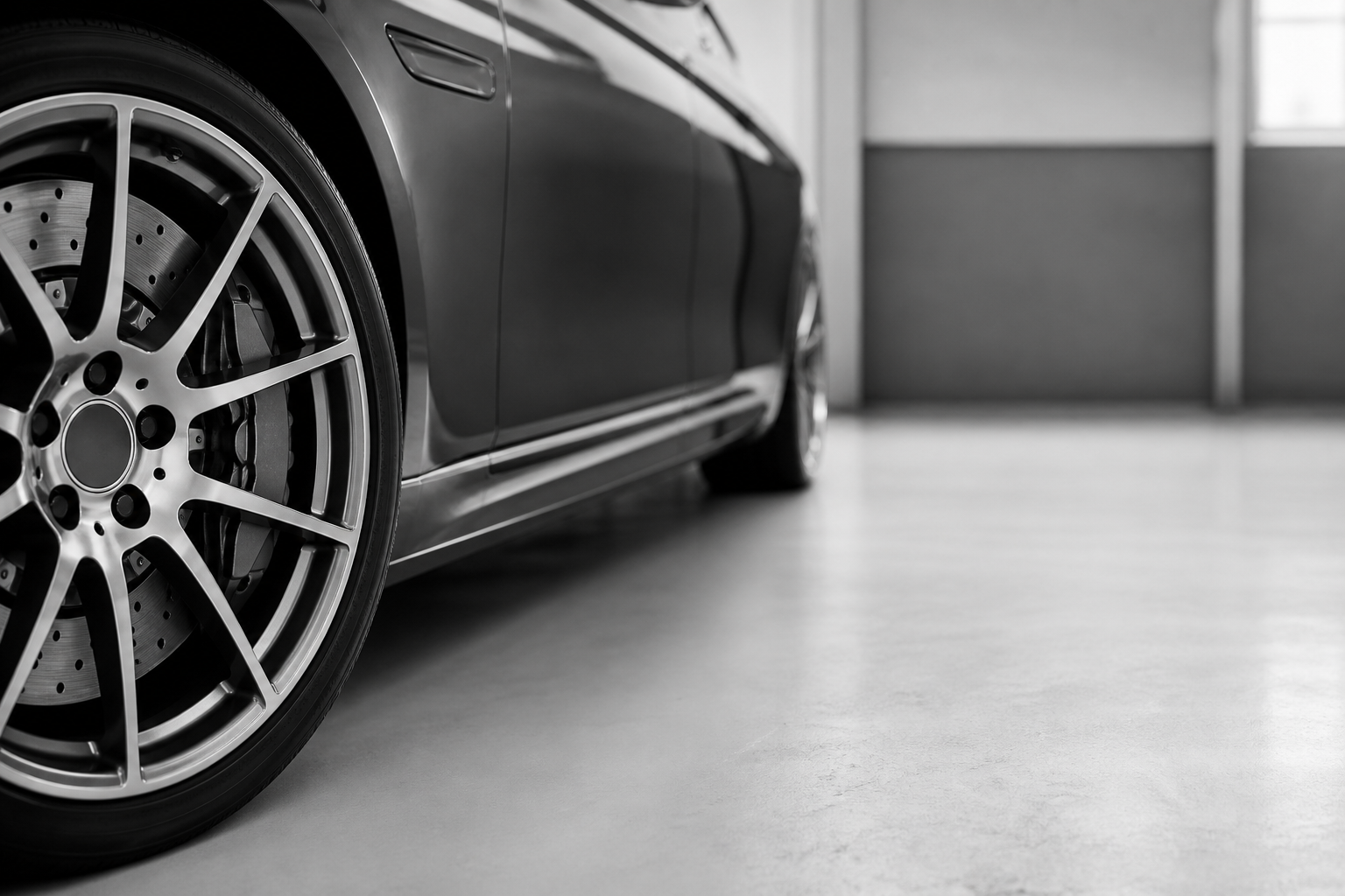 Monochrome wheel and brake detail in a workshop.