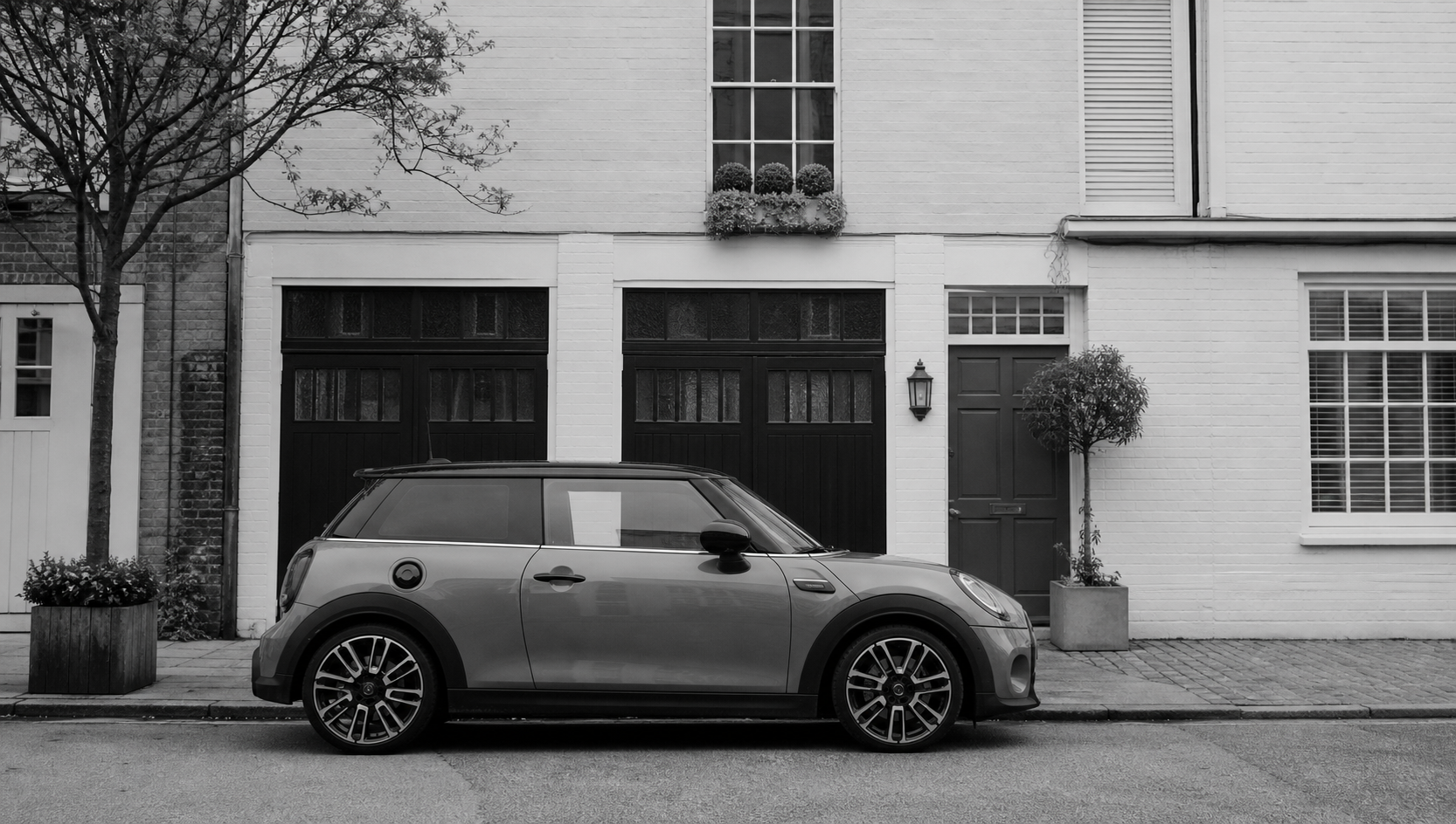 Monochrome grand tourer outside a minimal garage frontage.
